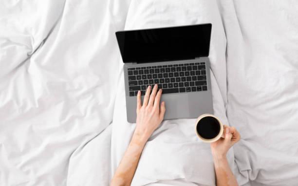 istock Woman using laptop with blank screen in bed during morning 1216751461
