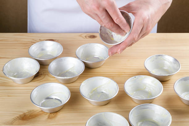 Woman spreading butter on small individual moulds stock photo