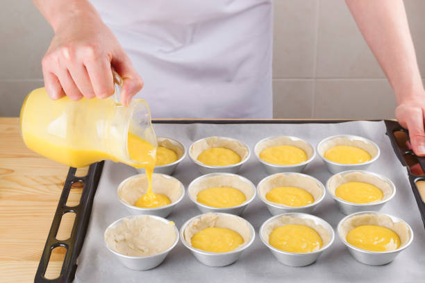 Woman pouring cream into small individual moulds stock photo
