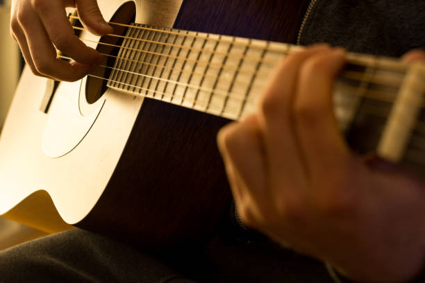 istock A man plays the guitar with warm light close up 1216755286