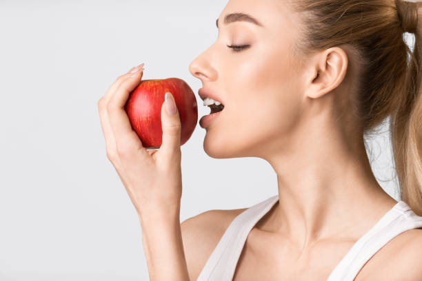istock Girl Biting Red Apple Posing On Gray Background, Studio Shot 1216755368