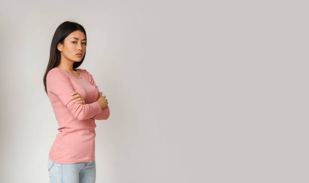 istock Angry asian girl looking at camera over grey background 1216755564
