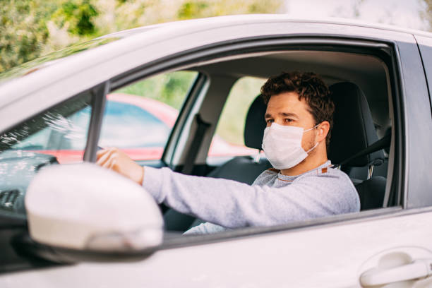 istock Man Wearing a Sterile Mask Driving a Car 1216755628