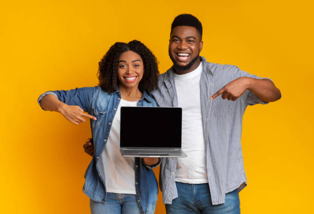 istock Great Website. Happy black couple pointing at laptop with black screen 1216755729