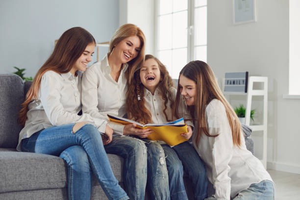 istock Mother with children reads a book while sitting on a sofa in a room. 1216756487