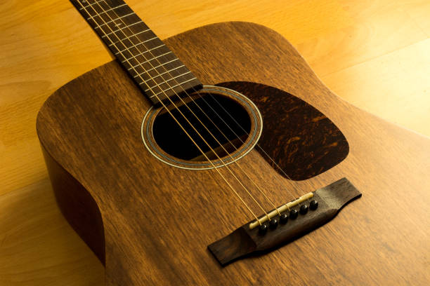 istock A brown wooden guitar on the floor with warm light from the side 1216756592