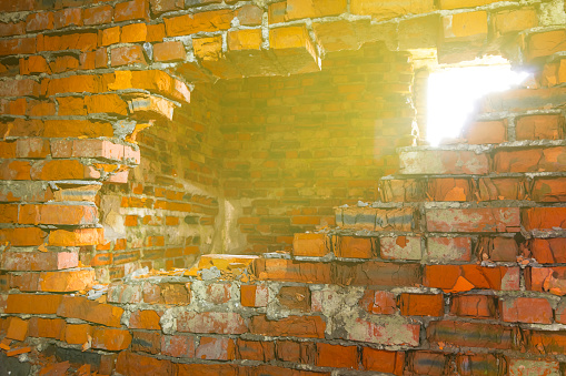 closeup red brick wall with hole lightened by a sun