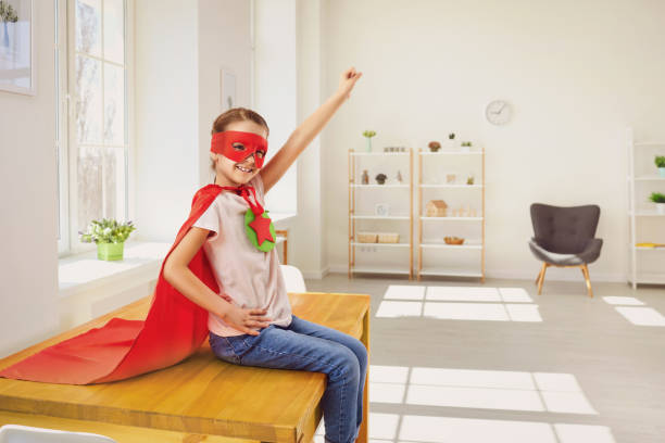 istock Child super hero.Kid smiling playing a superhero having fun in a room with a window. 1216757008
