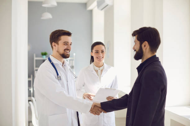 istock Handshake. Practicing doctor and patient shaking hands smiling at the clinic. 1216757752