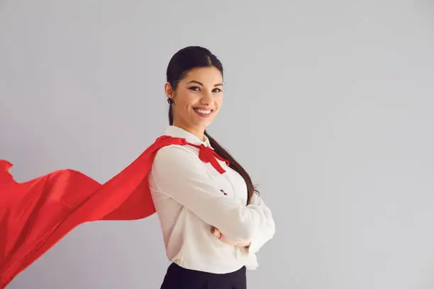 Happy woman in superhero costume laughs confident happy joyful on gray background.