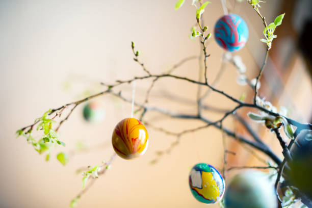 coloridos huevos de pascua de mármol en el arbusto sobre fondo borroso - orange sauce fotografías e imágenes de stock