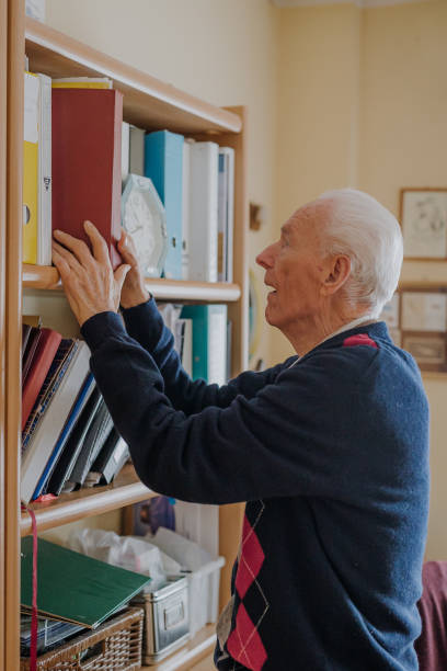 istock Elderly man reading book at home 1216760756
