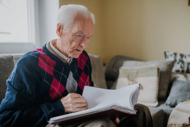 istock Elderly man reading book at home 1216760784