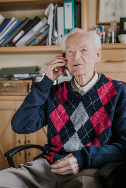 istock Elderly man talking on phone sitting at home 1216761709
