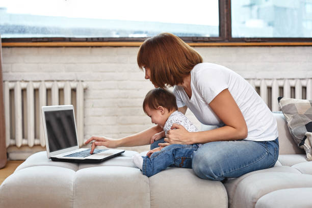 istock A woman with a child at a laptop sitting on a sofa. Work at home, freelancer, work during maternity leave for remote access 1216762227