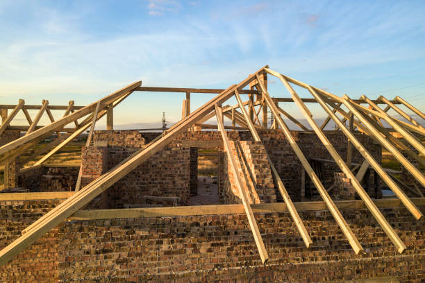 istock Private residential house with wooden roof frame structure under construction. Unfinished brick building under development. 1216763525