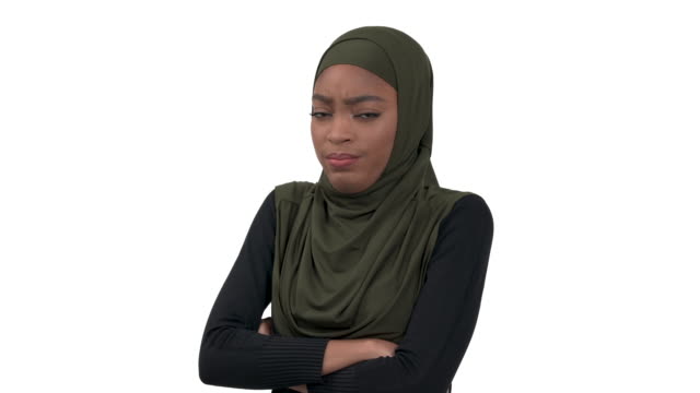 Close-up of strict African woman in hijab standing with her arms crossed, posing to camera. Isolated, over white background