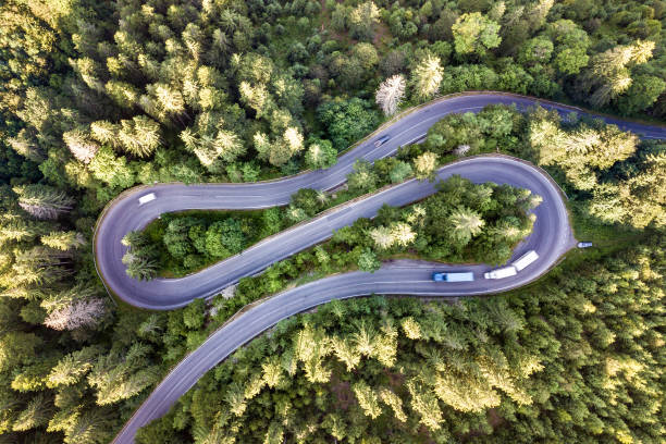 vista aerea della strada tortuosa in alta montagna passa attraverso fitte pinete verdi. - highway road street twisted foto e immagini stock