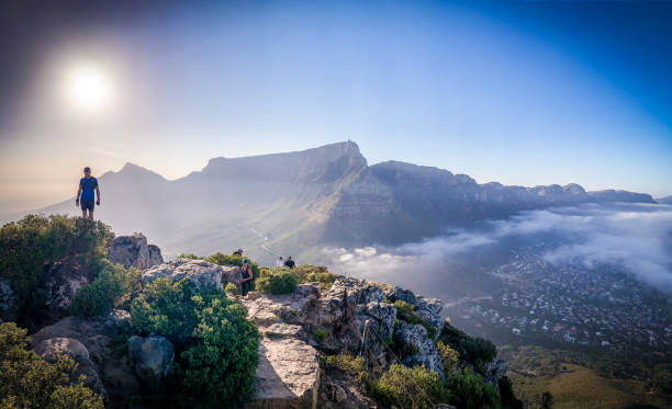 Hiker looking at Table Mountain A hiker/trail-runner stand on top of  Lions head during a morning run. Stopping to look at Table mountain with a panoramic view. table mountain south africa stock pictures, royalty-free photos & images