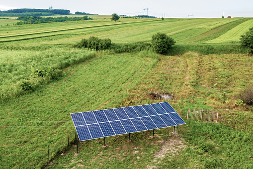 Aerial top down view of solar panels in green rural area.