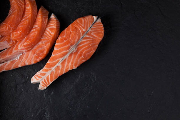 Salmon steak and slices on a black textured background Salmon steak and slices on a black textured background. sockeye salmon filet stock pictures, royalty-free photos & images