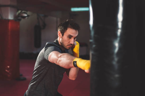 istock Boxer punching boxing bag in the gym 1216772687