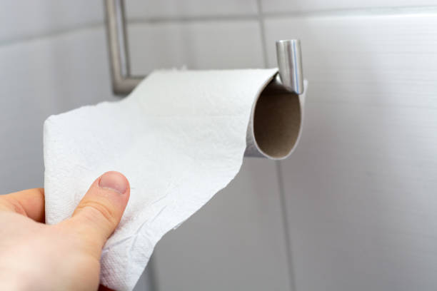 istock Man grabs toilet paper from an almost empty roll as a close up 1216772920