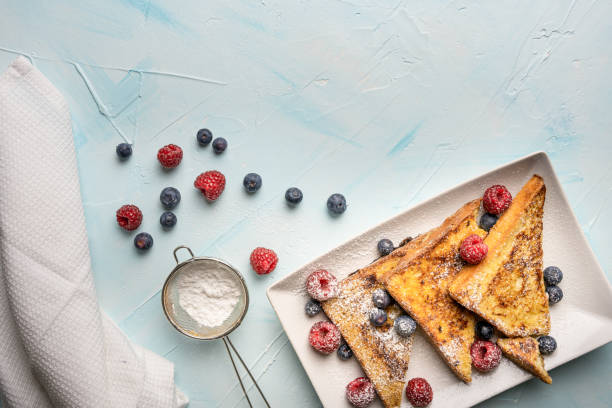 deliciosas tostadas francesas dulces con canela, vainilla y bayas frescas sobre fondo azul claro. desayuno rápido y fácil, vista superior y copia del espacio - french toast toast butter breakfast fotografías e imágenes de stock