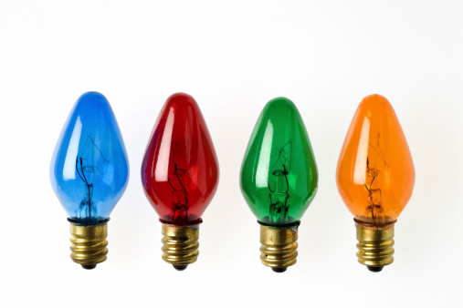 Four colored Christmas light bulbs on white