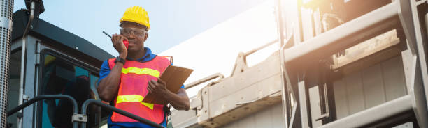 istock Black foreman worker working control the crane and forklift at Container cargo harbor to loading containers. African dock male staff with radio walkie-talkie for Logistics import export shipping concept. 1216775805