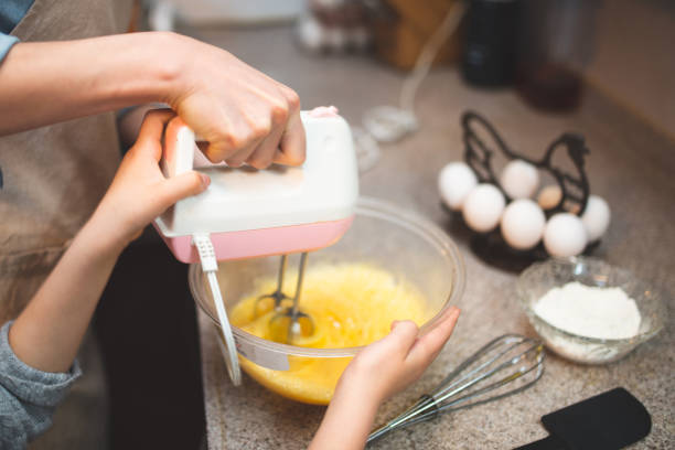 istock Mother and daughter making cake at home 1216777936