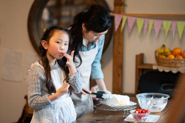 istock Mother and daughter making cake at home 1216777981
