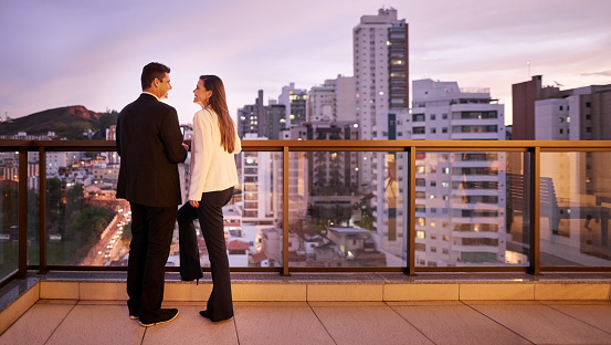 Shot of business partners standing in office balcony and smiling