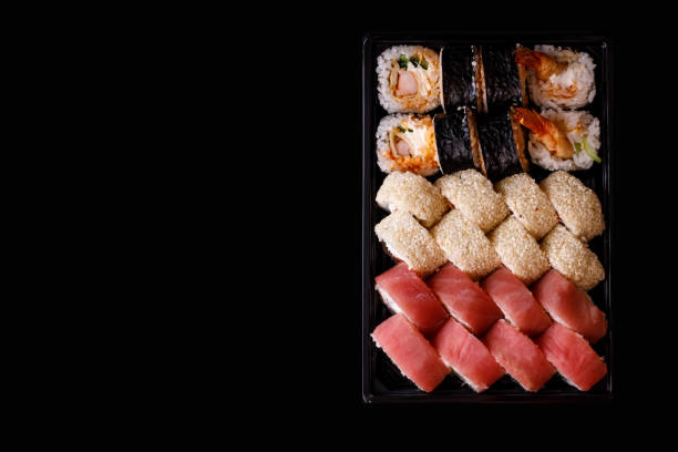 istock Sushi delivery. Set of rolls in a disposable box on a black background. 1216781067