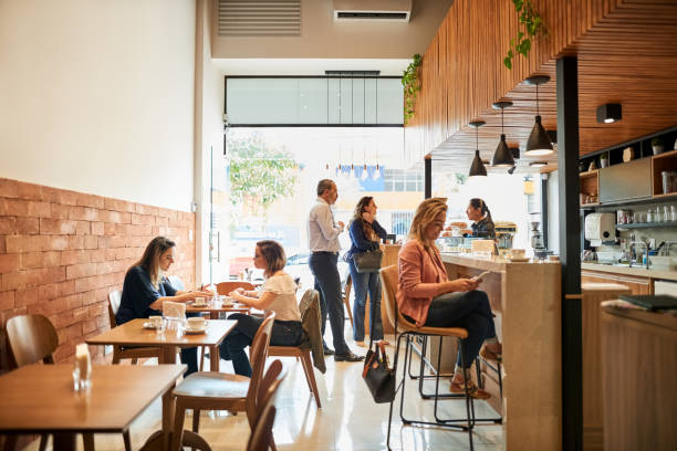 Chilling out at a coffee shop Shot of a people sitting at small coffee shop busy restaurant tables stock pictures, royalty-free photos & images
