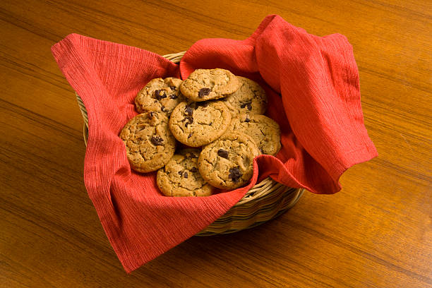 The Asian woman holding cookies in the hand on the yellow background.