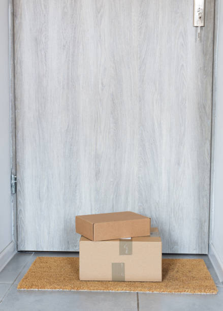 istock Parcel in cardboard box left on near door on rug. 1216783928
