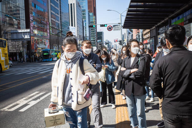 People at bus stop People are waiting buses to come at bus stop located at Gangnam area wearing mask on their face. This is a scene where many citizens are friendly and supportive of strict social distance and prevention of COVID19 disinfection. seoul bus stock pictures, royalty-free photos & images