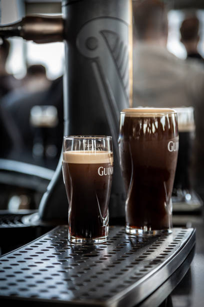 맥주 탭 앞에서 기네스 맥주 두 잔을 선별적으로 클로즈업합니다. - guinness 뉴스 사진 이미지