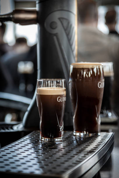 Selective focus closeup of two full glass of Guinness beer in front of a beer tap. stock photo