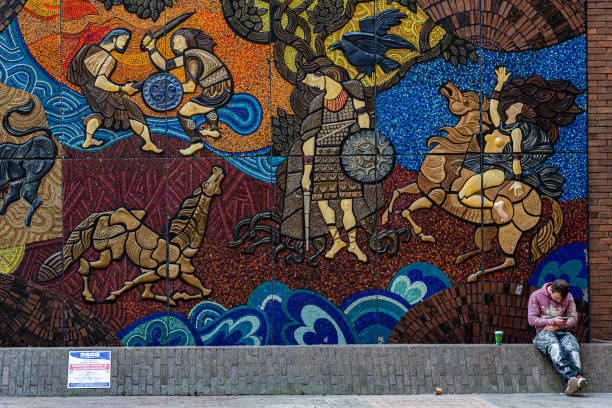 male craftsman sitting leaning against a large public mosaic art wall outdoors. - dublin ireland brick built structure building exterior imagens e fotografias de stock