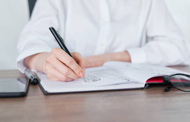 istock Business Woman Writing with pen in notepad 1216786913