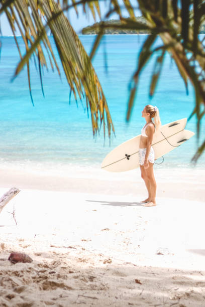 istock Girl with her surfboard walking on the beach 1216786927