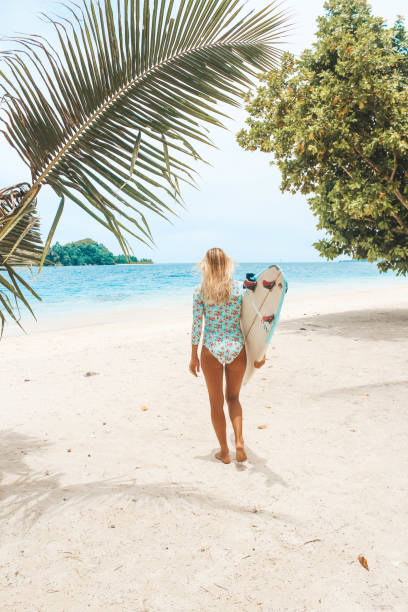 istock Girl with her surfboard walking on the beach 1216787895