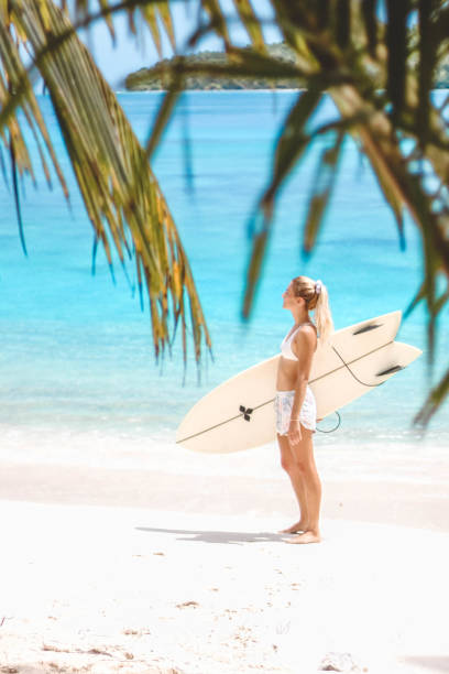 istock Girl with her surfboard walking on the beach 1216787955
