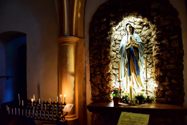 Mondsee, Austria - 08.05.2016: Statue of the Virgin Mary in a blue cape at Basilika St. Michael, candles are burning nearby.