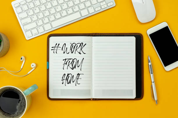 istock Table top view aerial image of accessories office desk for work from home background concept.Flat lay of white mobile phone & keyboard and coffee with earphone on modern rustic yellow paper.copy space 1216789413