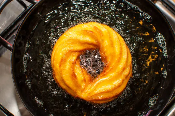 Fritters made from cream-puff dough, austrian desert speciality, cooking in oil in metal pan