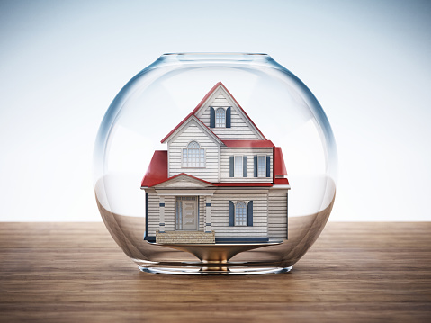 House standing inside fish bowl on wooden surface.