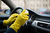 Man's hands wearing rubber gloves disinfecting and cleaning car interior